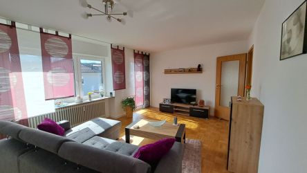 Modern eingerichtetes Wohnzimmer mit grauer Eckcouch, Couchtisch aus Holz und dekorativen Bildern an der Wand.