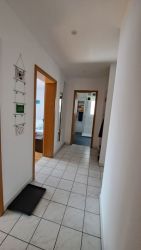 Heller Flur mit weißen Fliesen und Zugang zu Schlafzimmer und Bad in der Ferienwohnung.